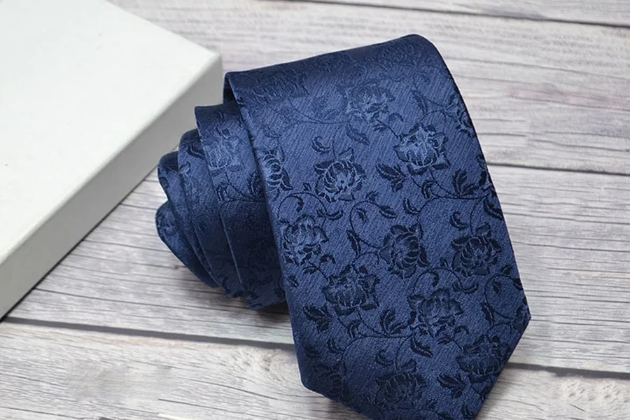 Rolled navy floral tie beside a plain presentation box