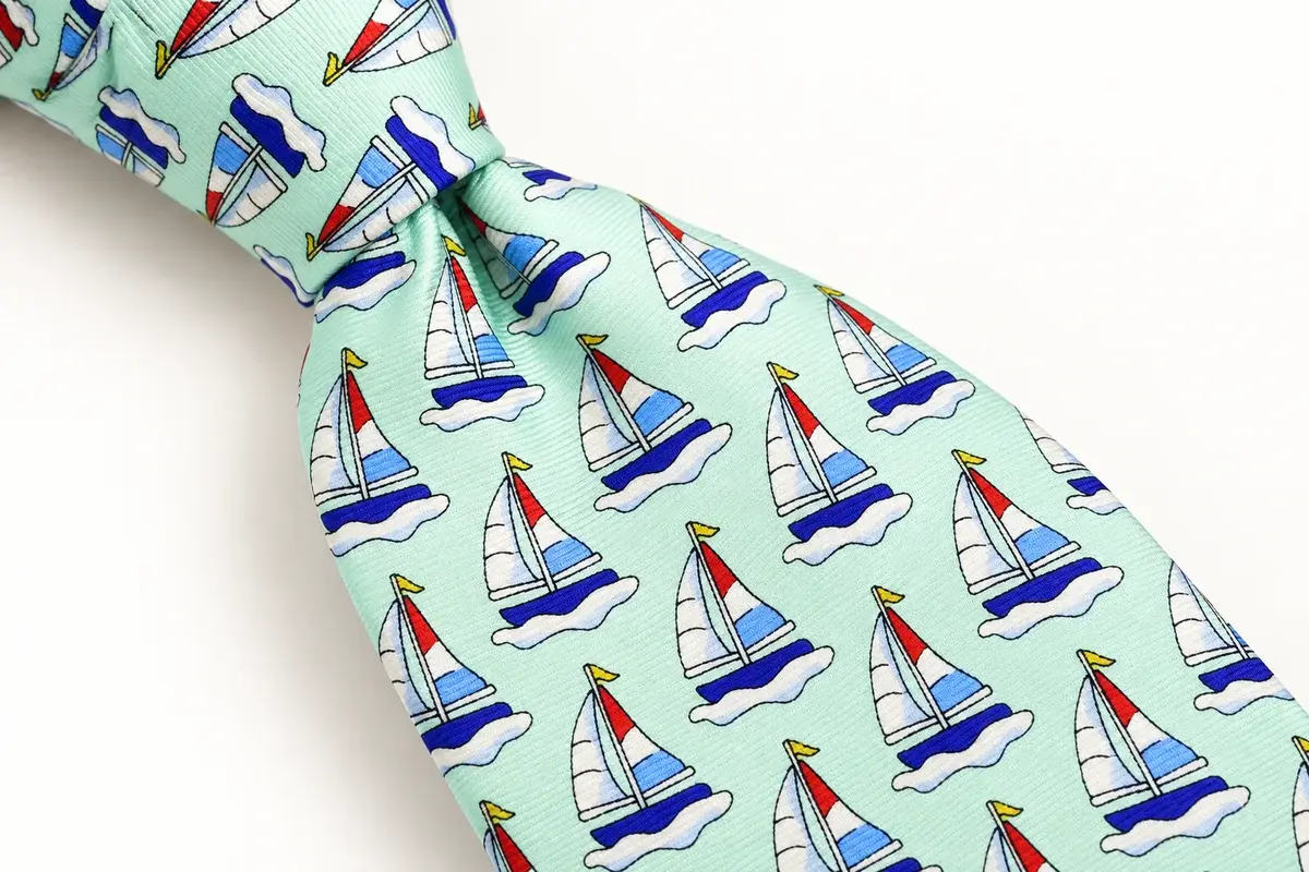 Close-up of sailboat patterns across a light green tie knot and blade.