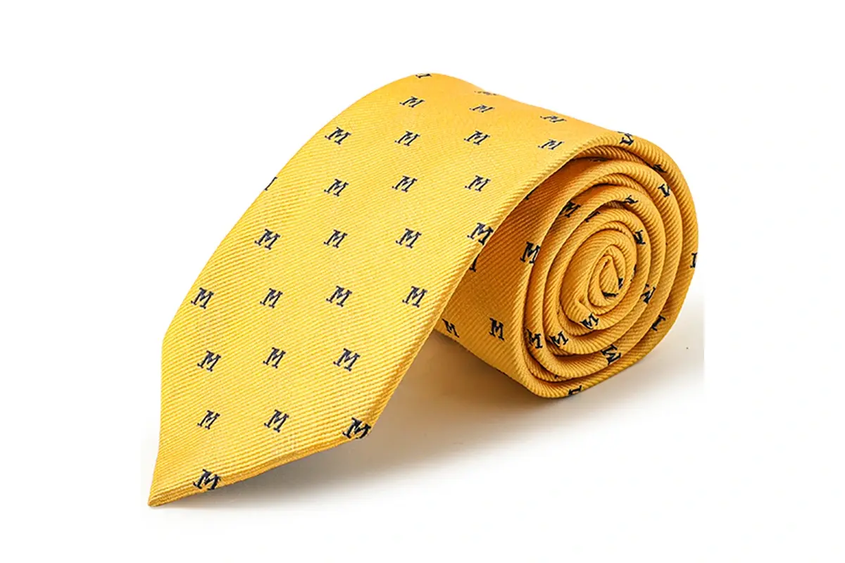 A rolled yellow tie with small repeating dark monograms.