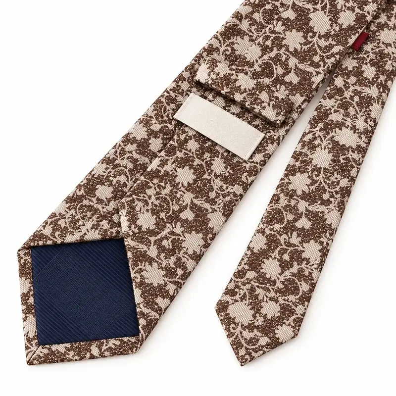 Ivory and brown botanical printed tie with dark tipping and a blank label.