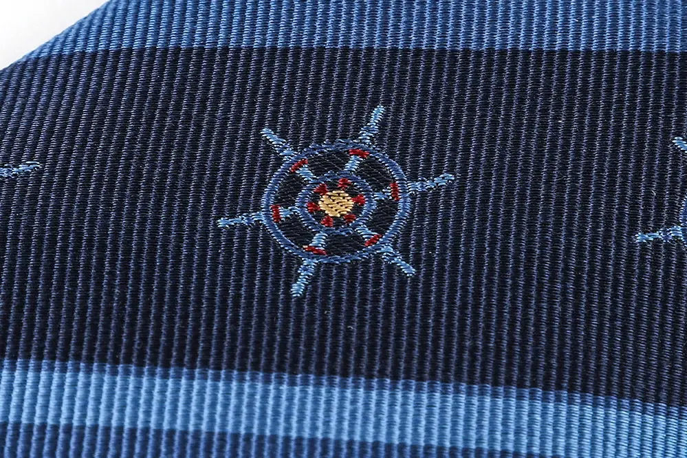 Ship wheel motif on blue striped necktie fabric.