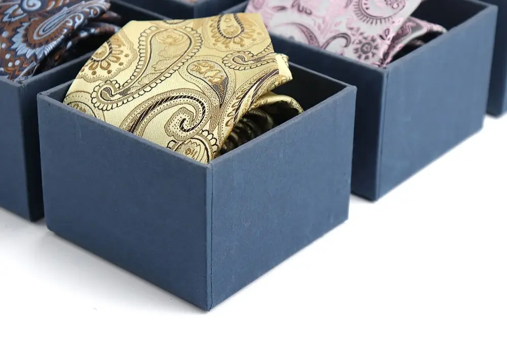 Paisley neckties arranged in individual blue presentation boxes.