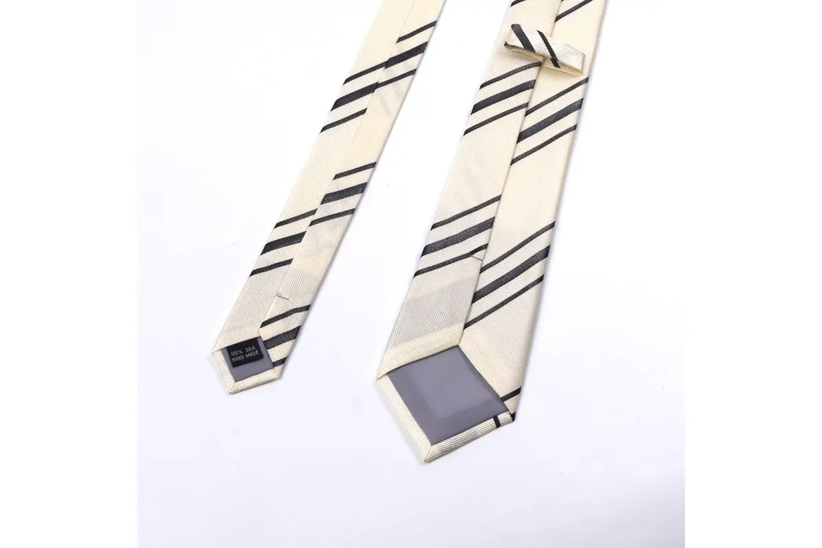 Cream tie with dark diagonal stripes shown from reverse with a small label.