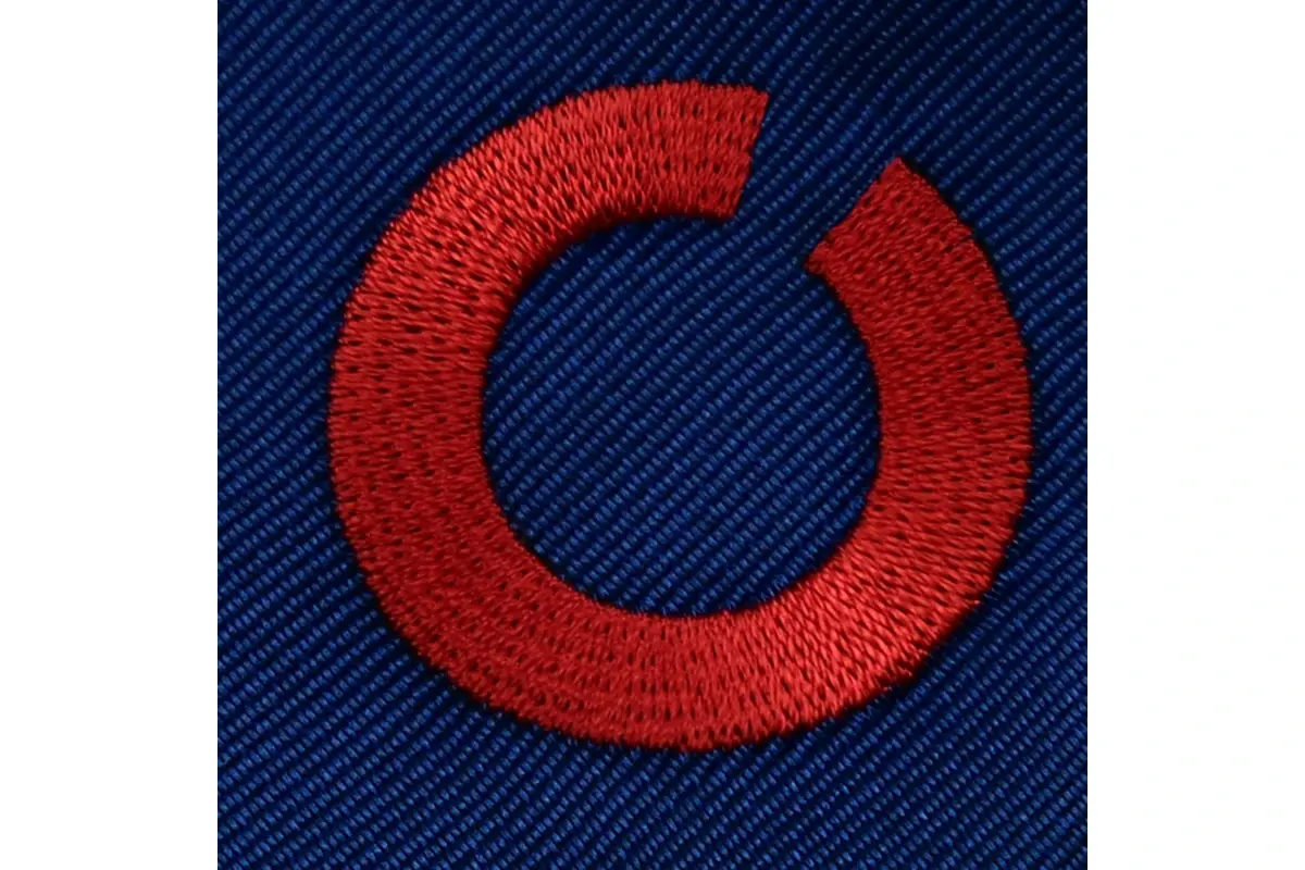 Close-up of a red embroidered circular mark on navy tie fabric.