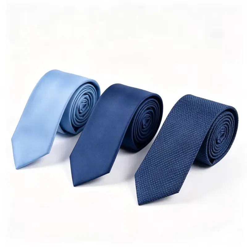 Three rolled plain ties in light blue and navy with different surface textures.