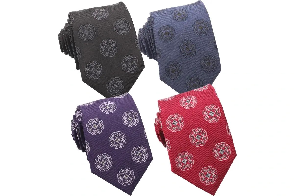 Four ties in black, blue, purple and red with repeating round emblems.