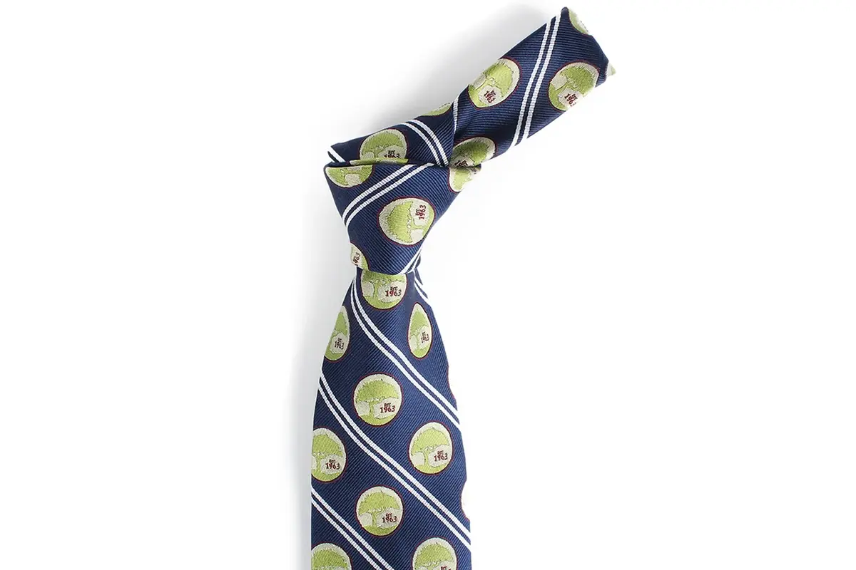 Knotted navy tie with repeated green circular marks between pale diagonal.