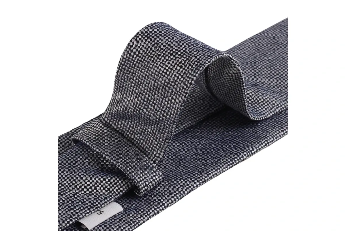 Close-up of a grey woven tie showing the fabric texture and reverse keeper loop.