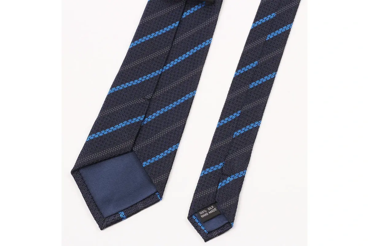 A dark tie with blue diagonal stripes, with tipping, center seam and care label.