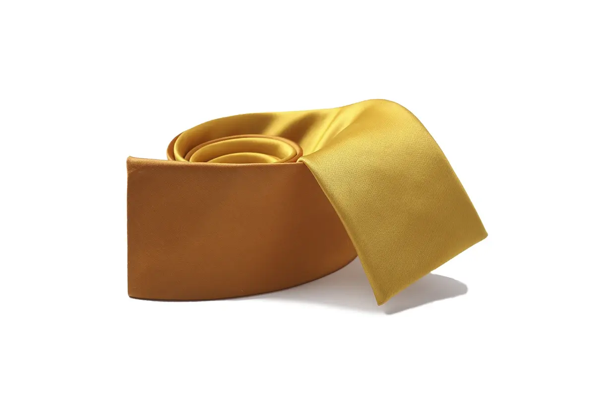 Gold-colored tie loosely rolled to show its smooth reflective surface.