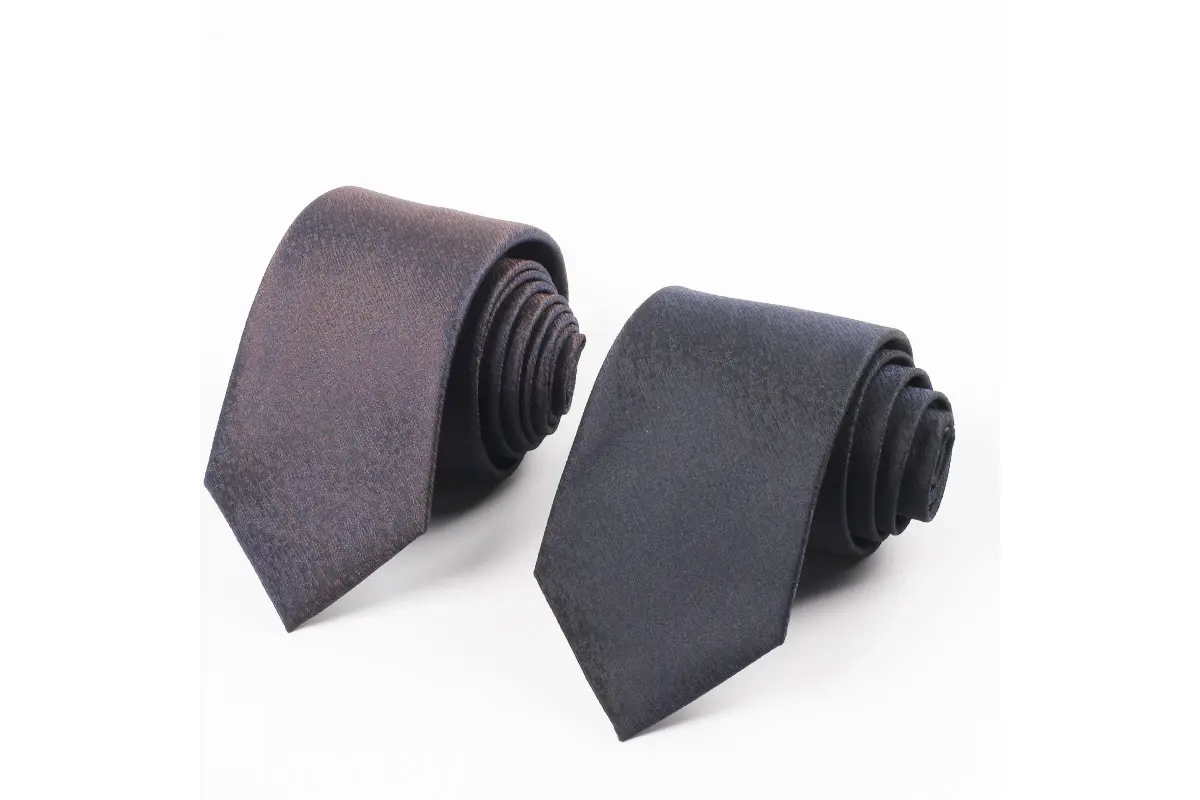 Two rolled ties in muted mauve and dark gray showing fine surface texture.