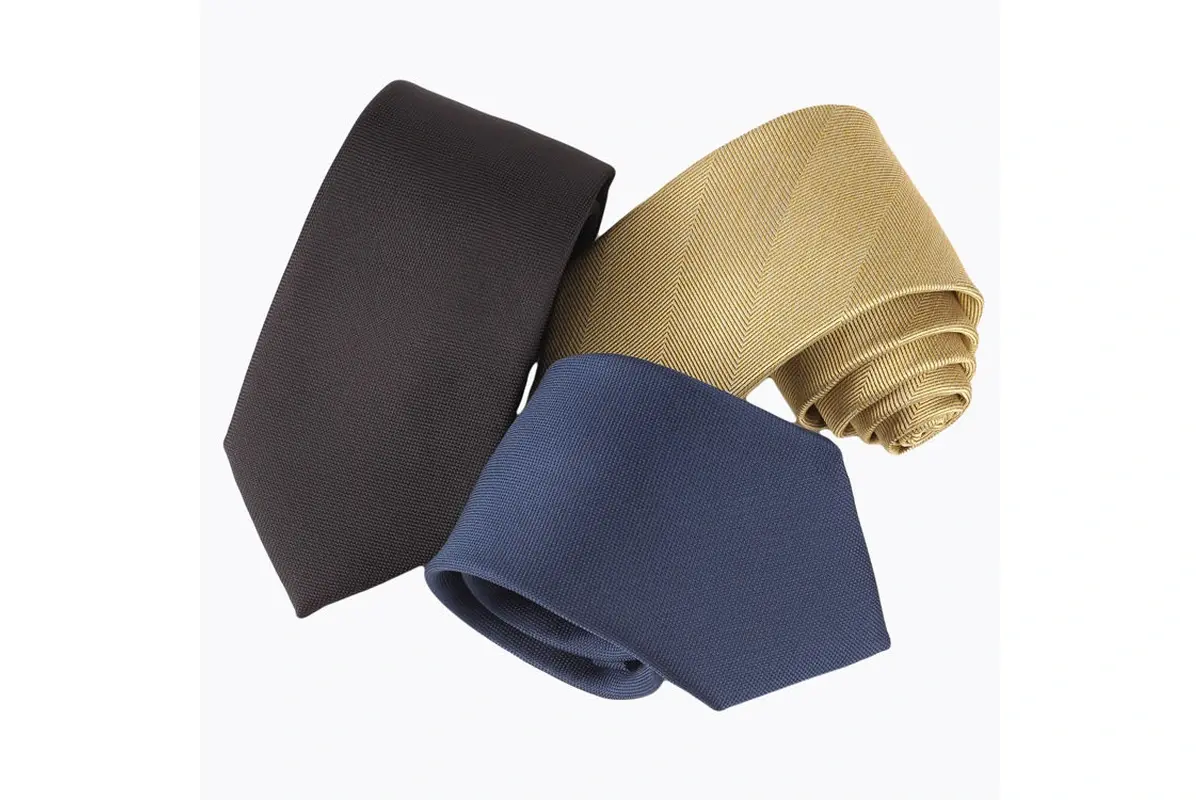 Three rolled plain ties in charcoal, gold and muted navy.