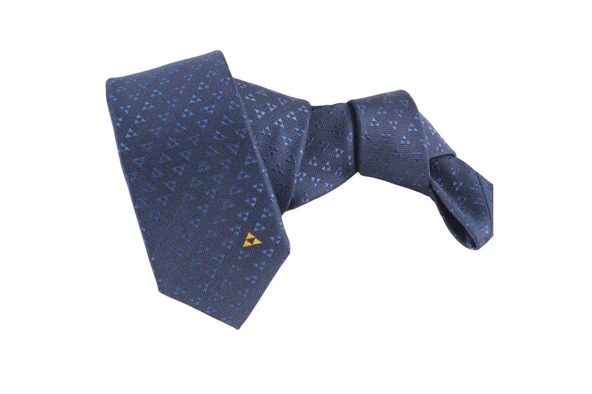 Knotted navy patterned tie with small gold geometric emblem near blade tip.