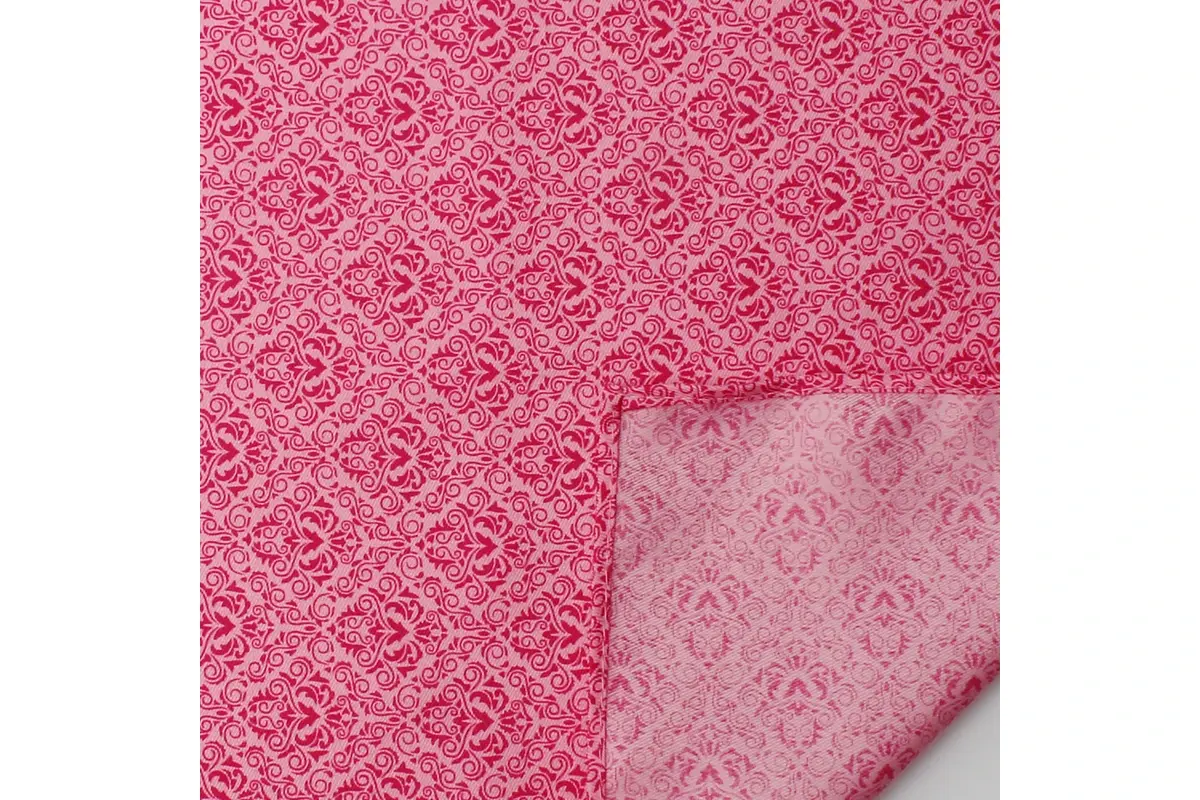 Pink jacquard fabric folded back to show its patterned face and lighter reverse.