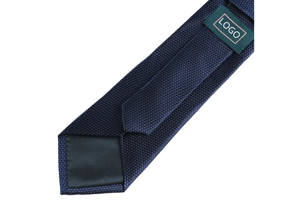 A navy textured tie with center seam, folded edges, tipping and sample label.