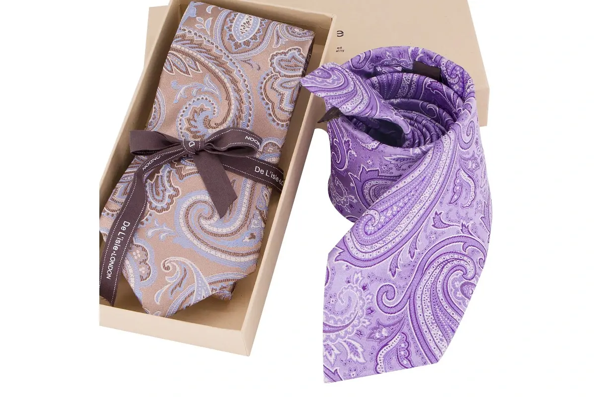 Purple paisley tie and matching pocket square arranged with an open gift box.