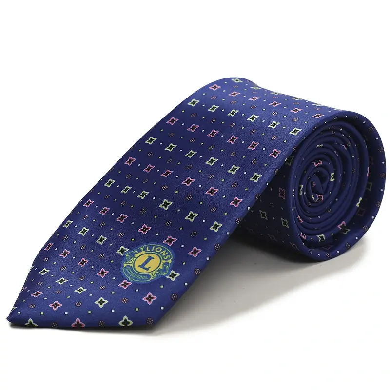 Rolled blue tie with repeating geometric motifs and a circular emblem.
