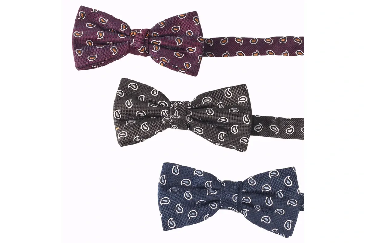 Three pre-tied bow ties in burgundy, black and navy with paisley motifs.