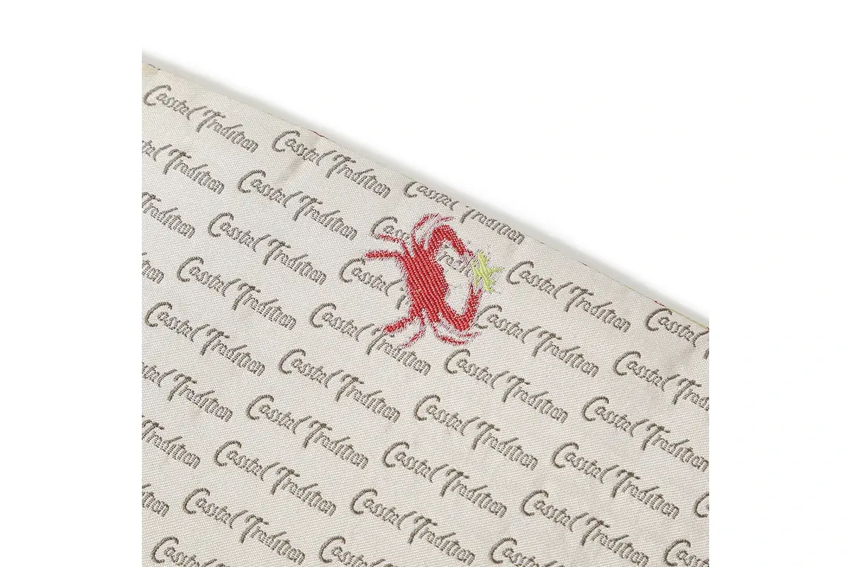 Fine repeated lettering and a red lobster symbol on a cream tie surface.