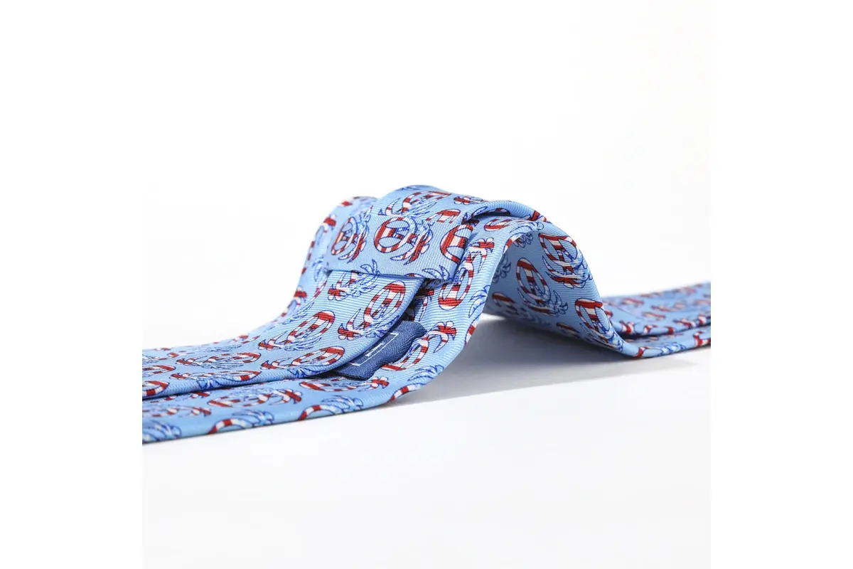Light blue tie showing detailed repeated red, white and blue circular logos.