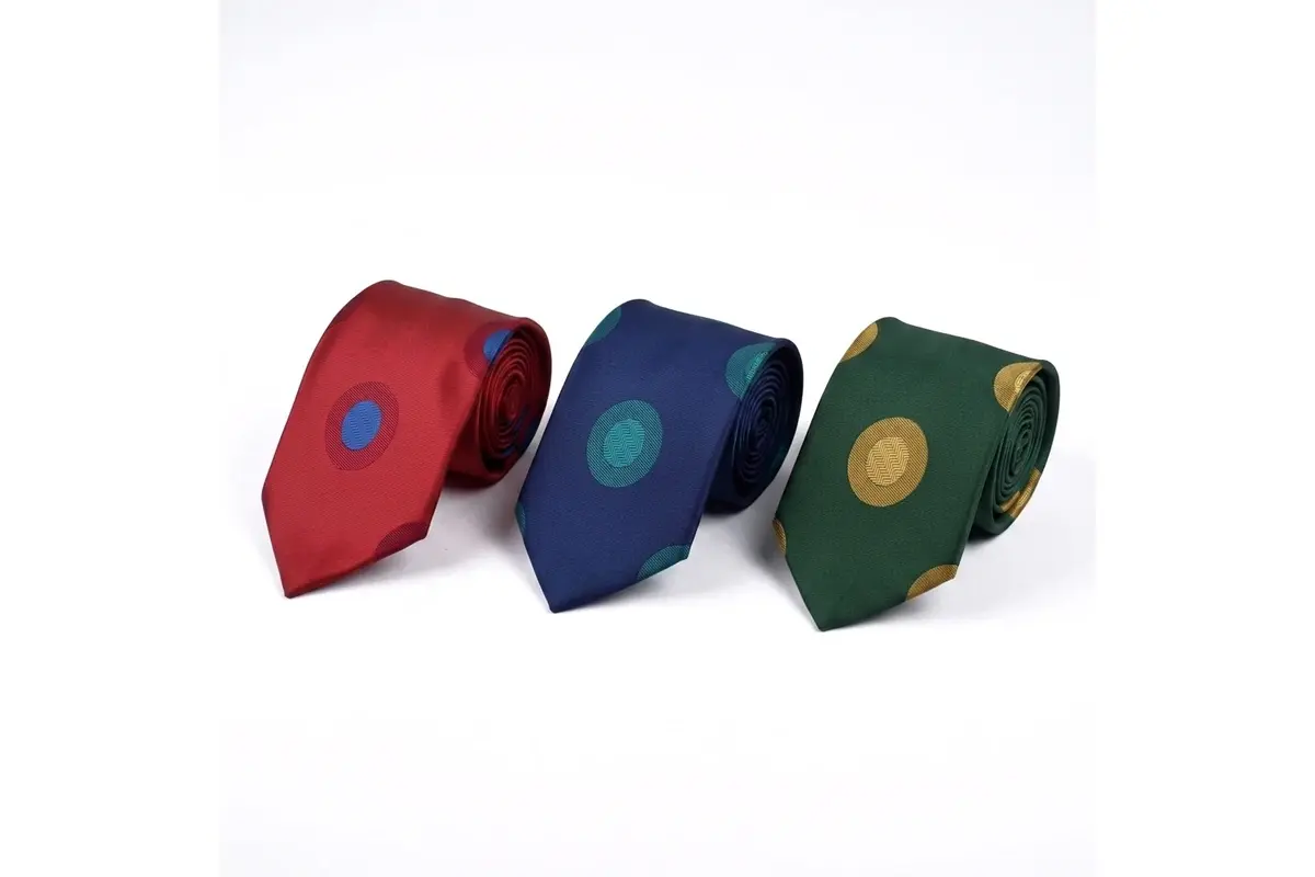 Red, navy and green ties with contrasting circular emblem motifs.