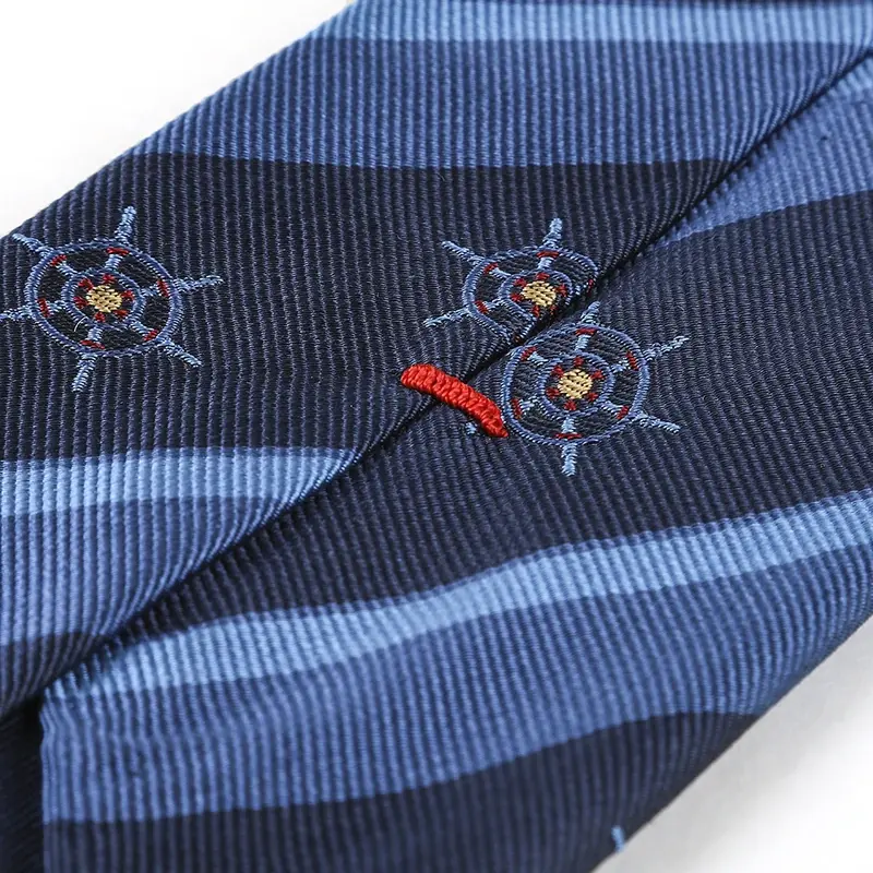 Close-up of ship-wheel motifs, diagonal stripes and a red stitch on a navy tie.