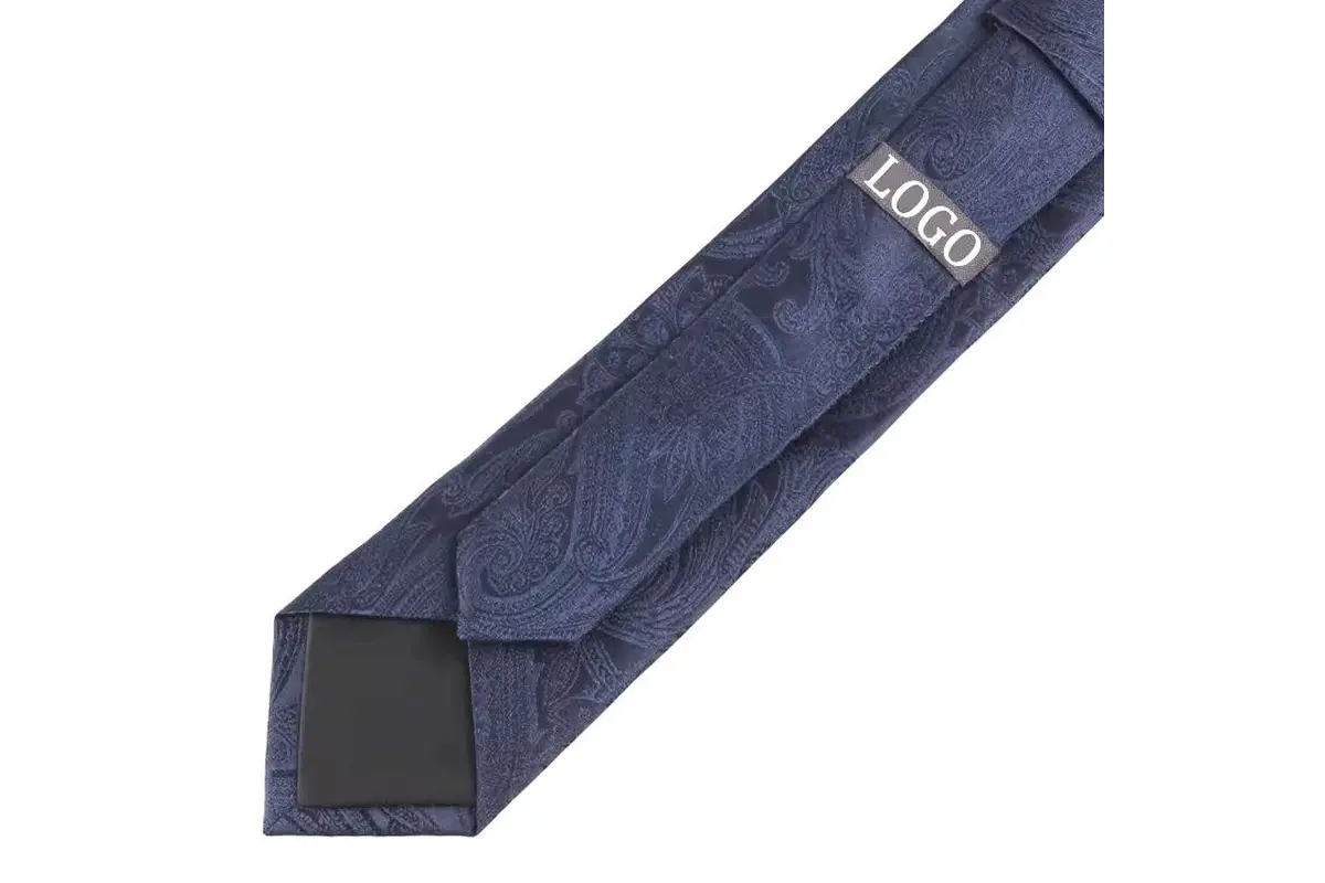 Navy paisley tie reverse with a sample logo label, center seam and dark tipping.