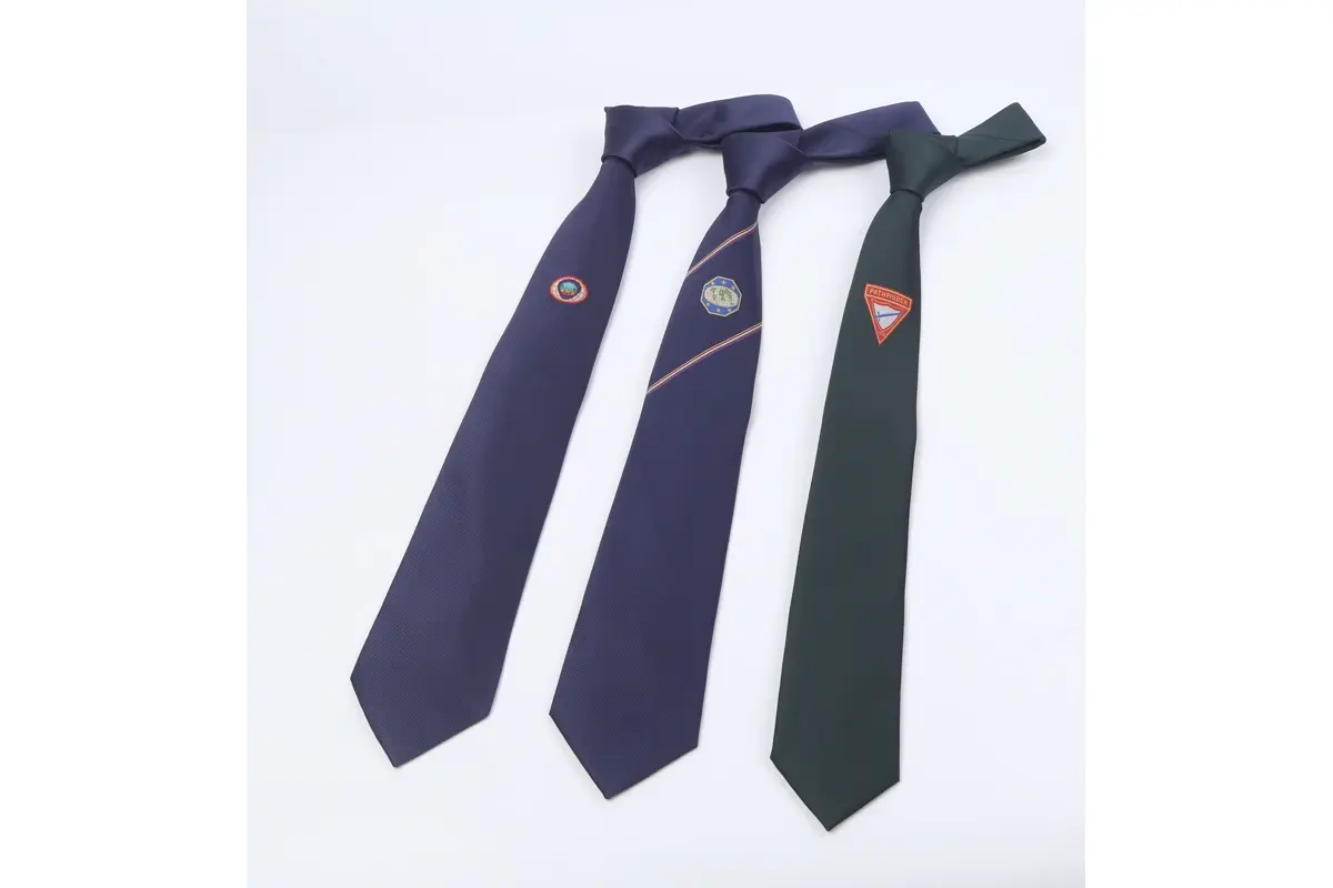 Three full knotted ties with placed emblems on dark blue and green blades.