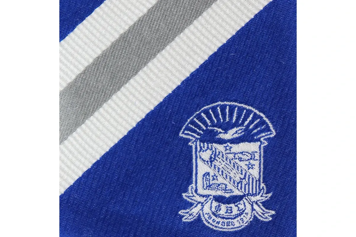 Close-up of a pale crest woven into a blue tie beside white and grey stripes.