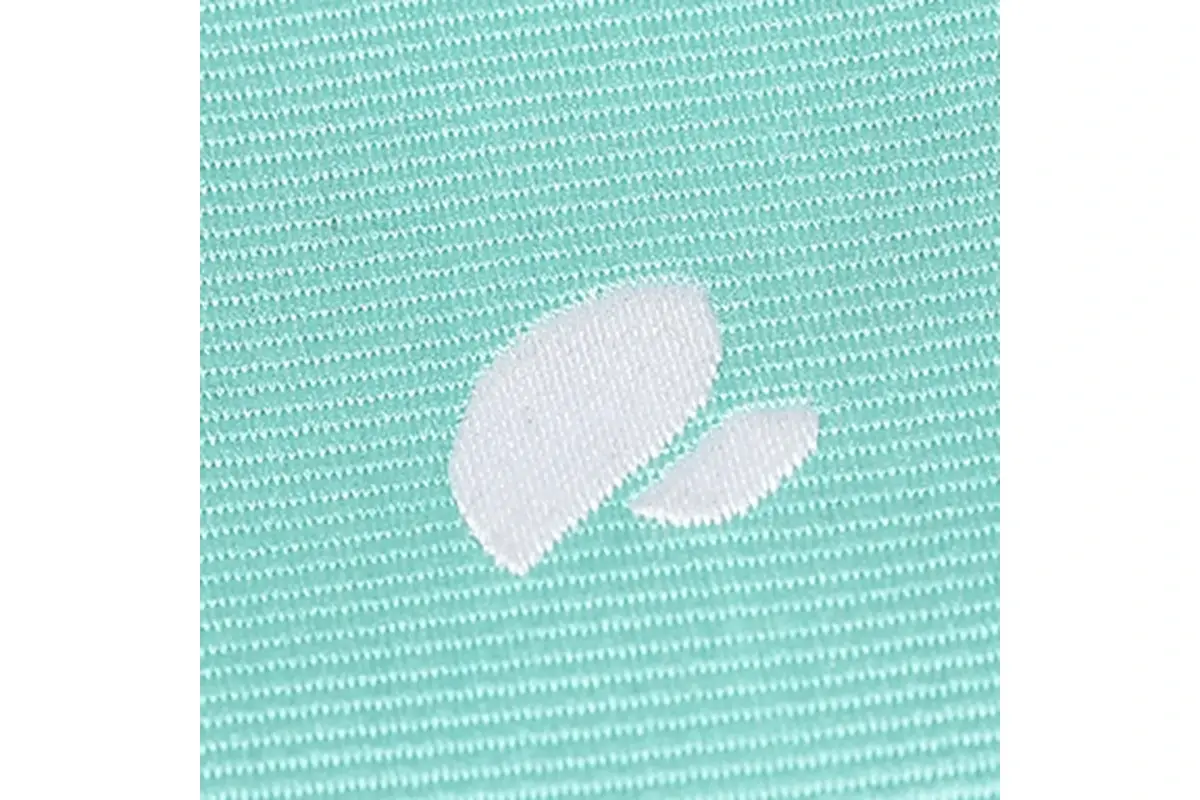 Close-up of a white leaf-shaped motif in mint-green woven fabric.