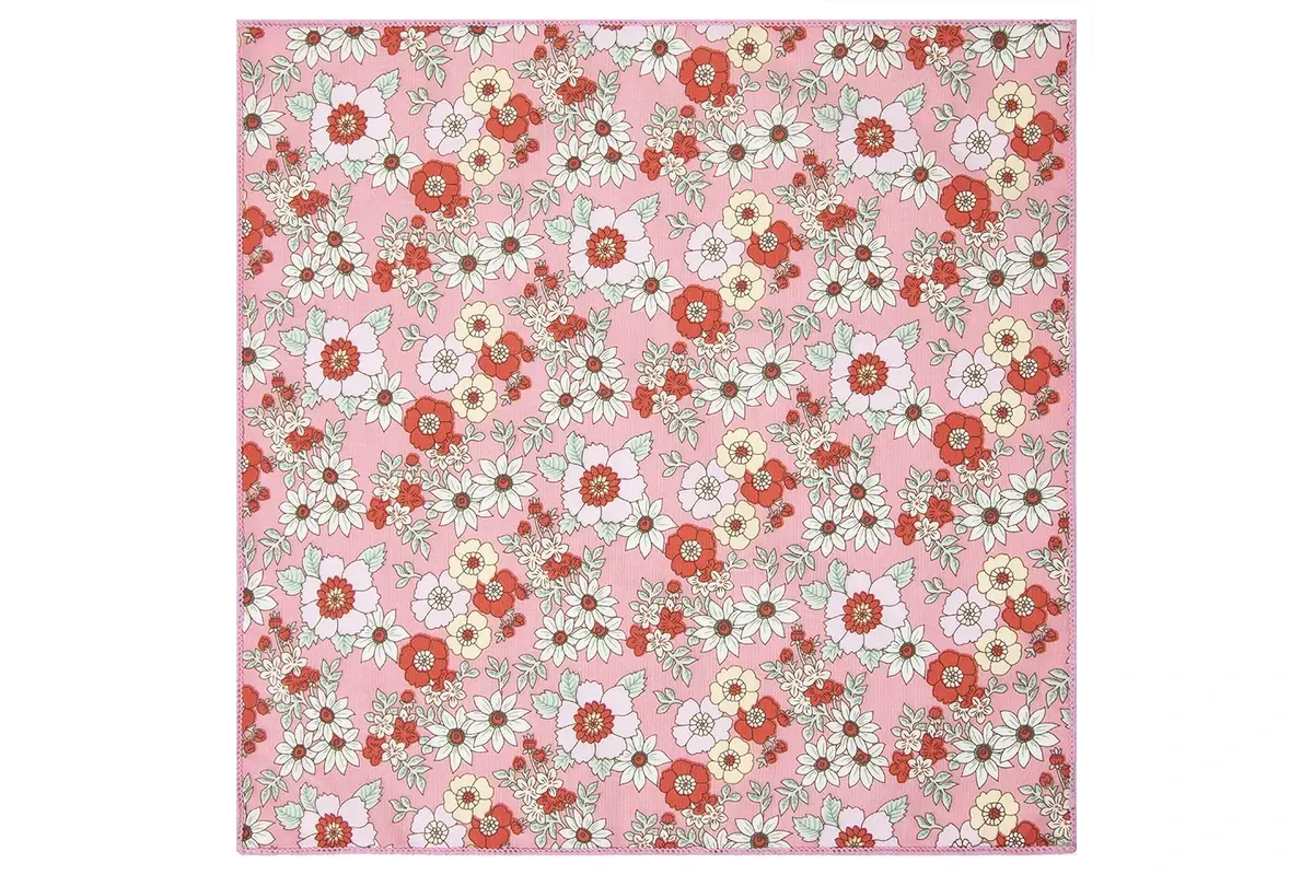 Pink fabric surface with red and white flowers and pale green leaves.