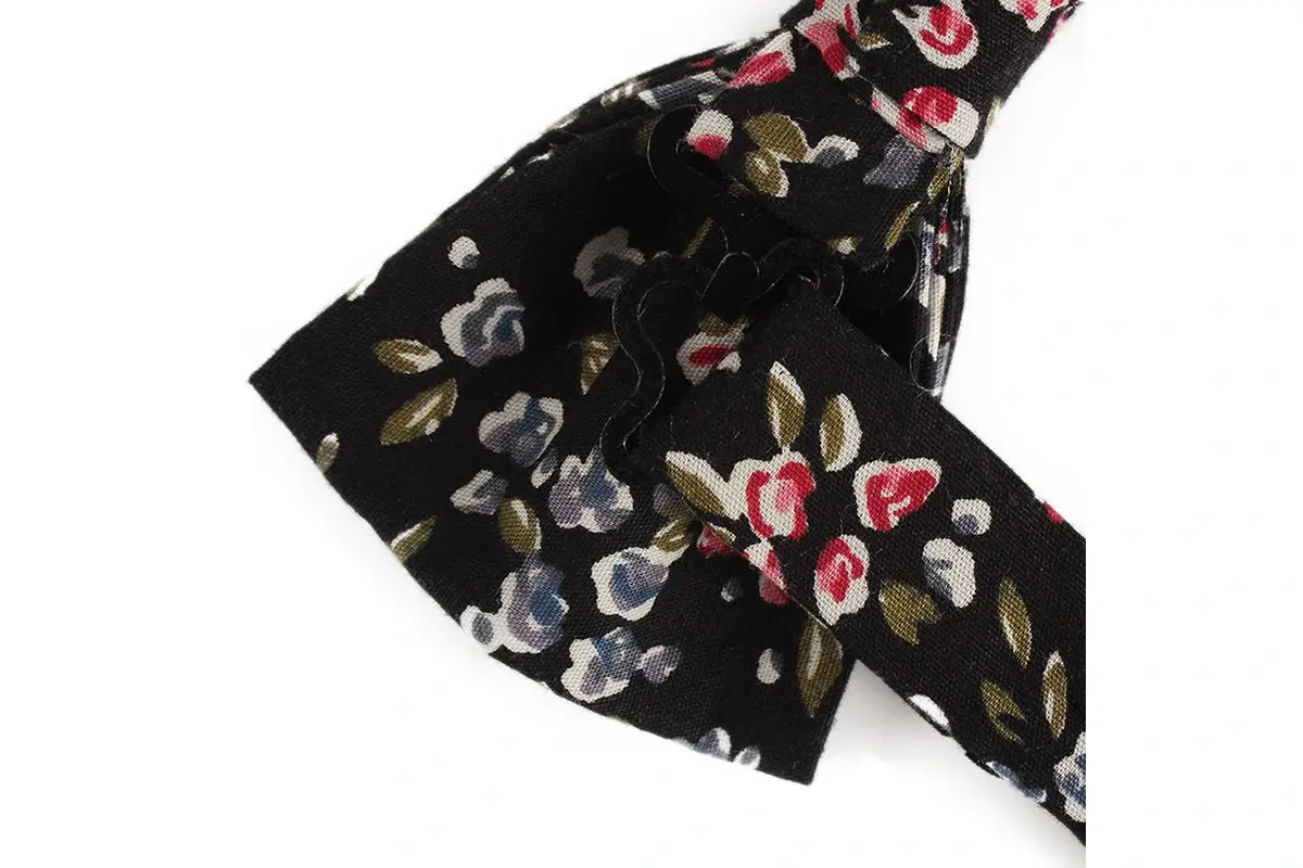 Close view of a black self-tie bow with red, white and gray floral motifs.