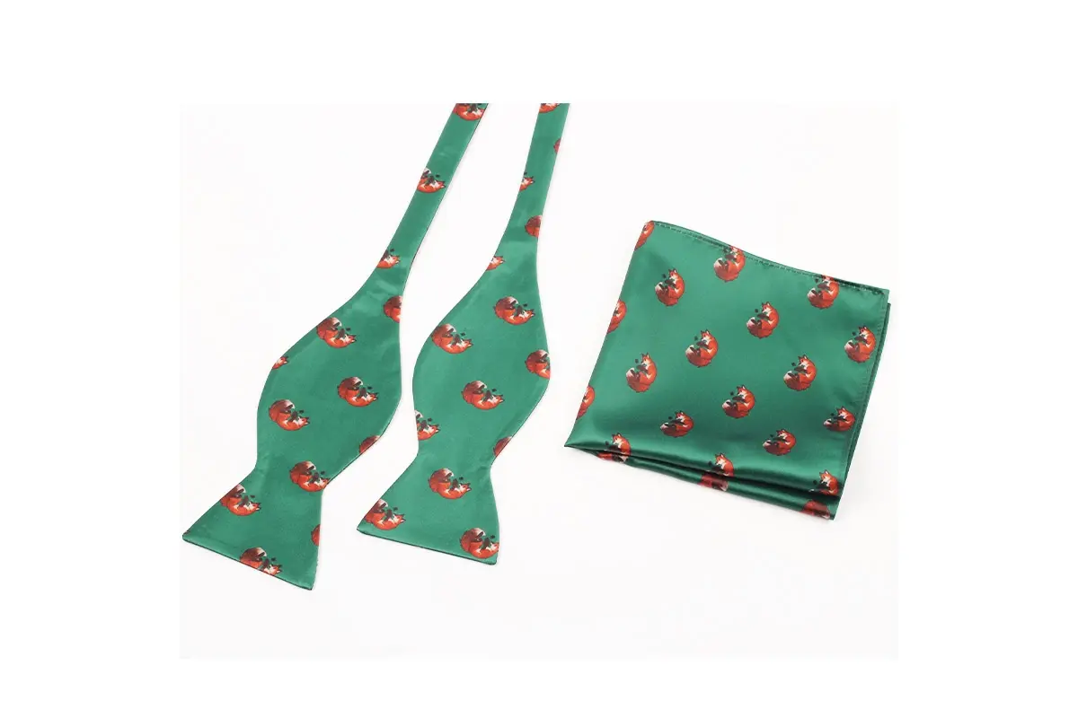 Two green self-tie bow ties and matching pocket square with repeated red motifs.
