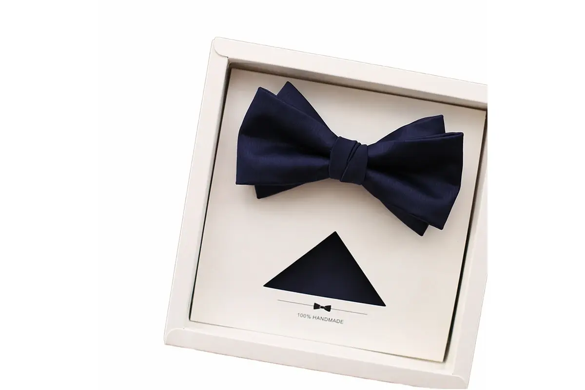 Navy bow tie displayed in a white presentation frame with a dark insert.