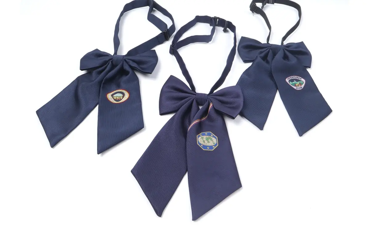 Three navy neck bows with long tails and circular sample tags.