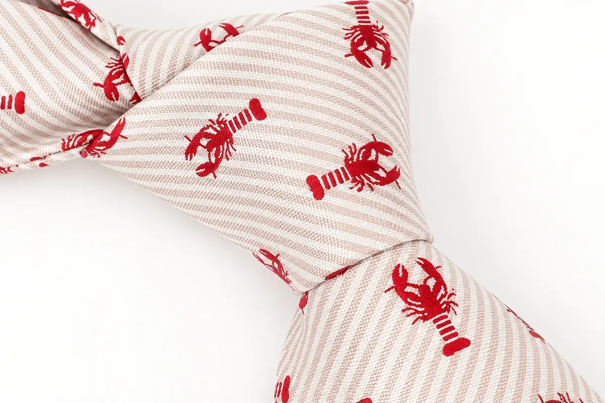red lobster motifs and fine pale diagonal stripes across a cream tie knot.