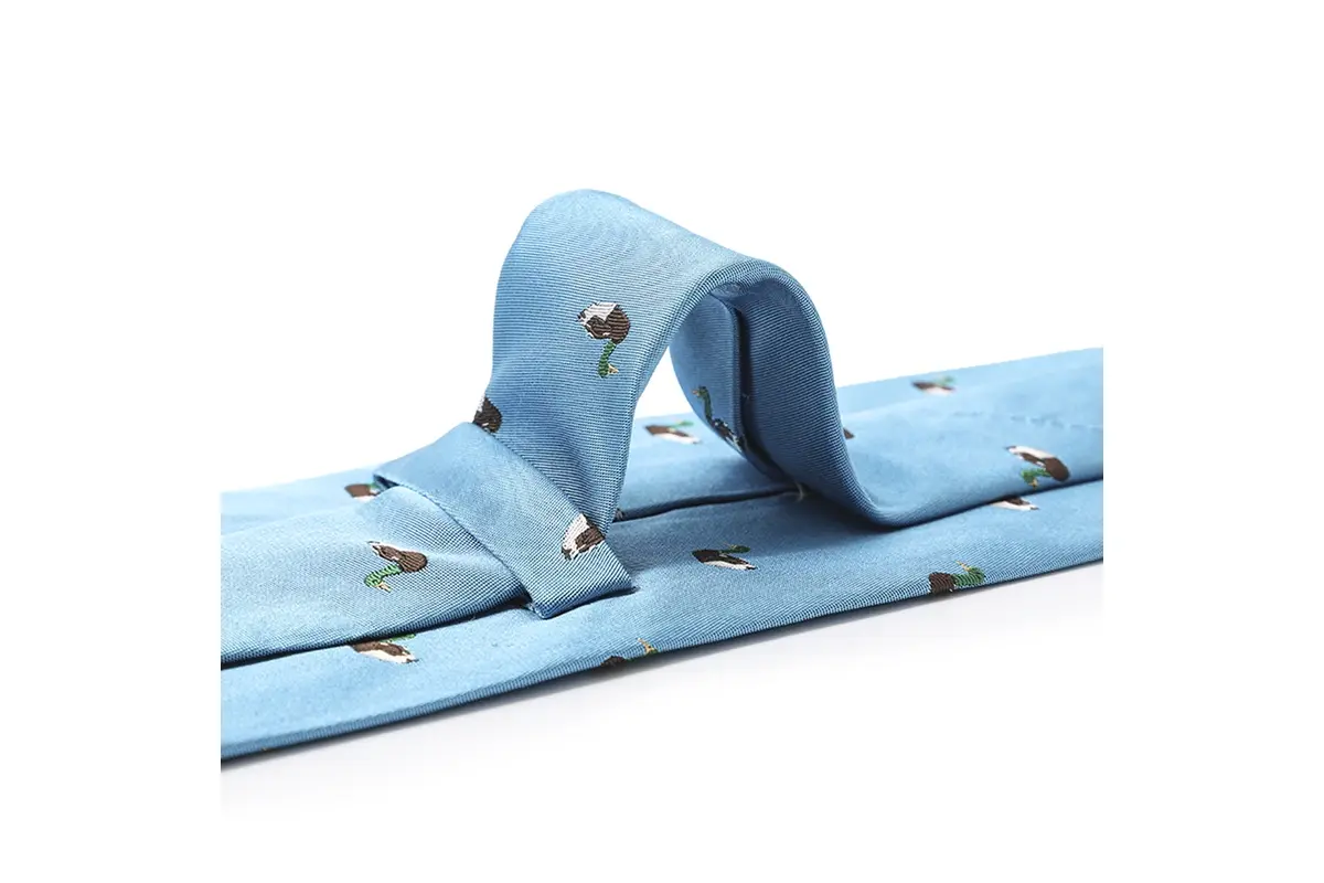 Light blue tie with small duck motifs arranged in a soft loop.