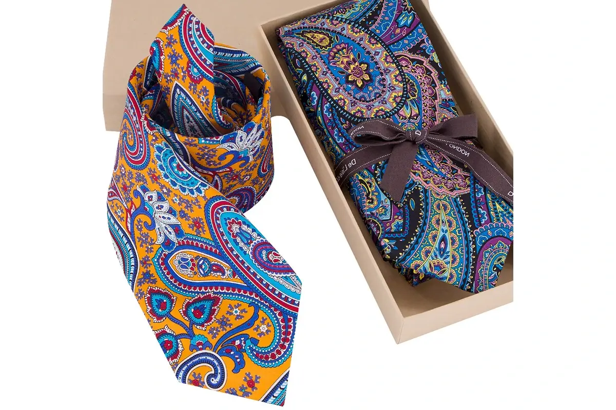 Colorful paisley ties shown rolled and arranged inside a gift box.