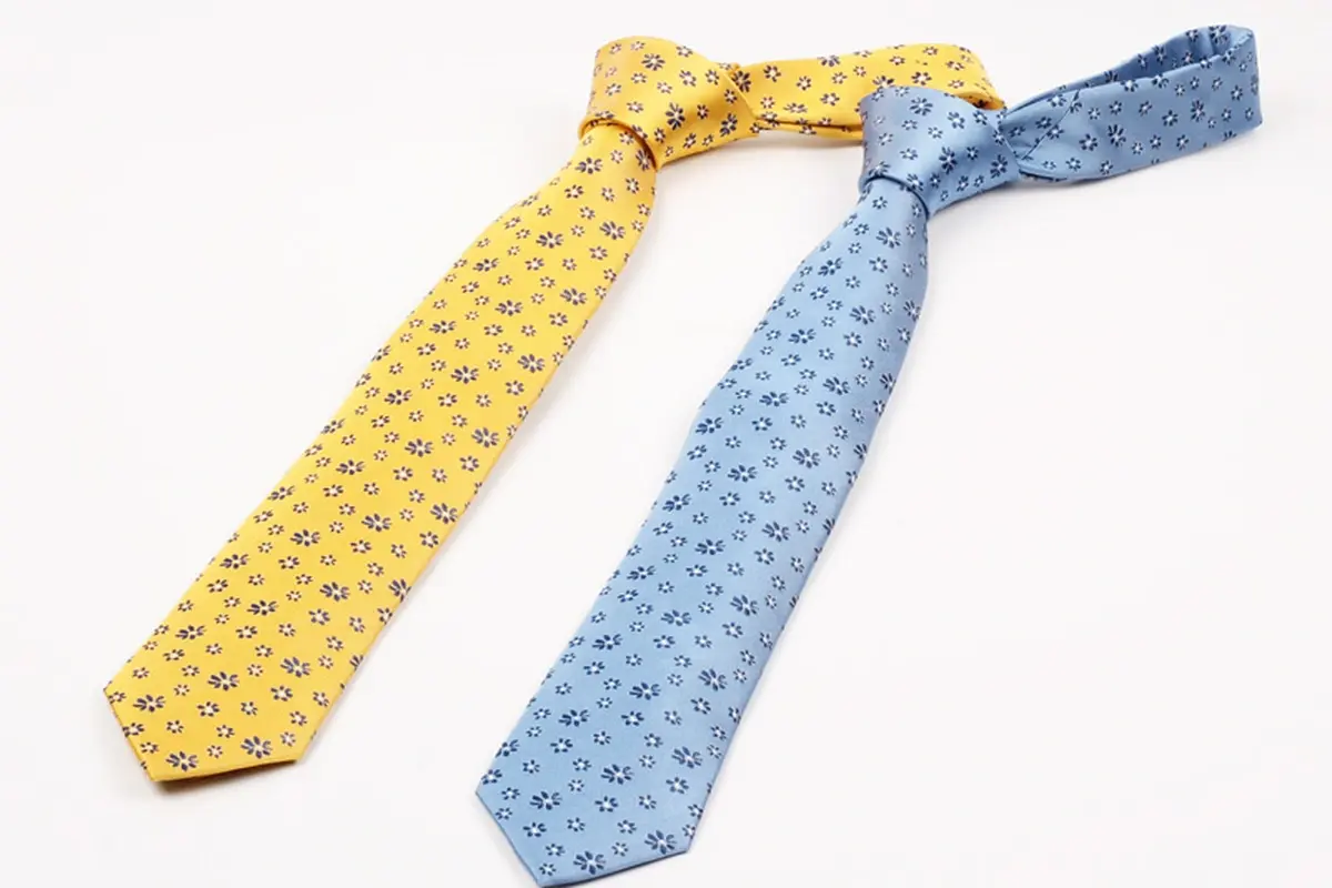 Yellow and light blue patterned ties laid out with knots and tapered blades.