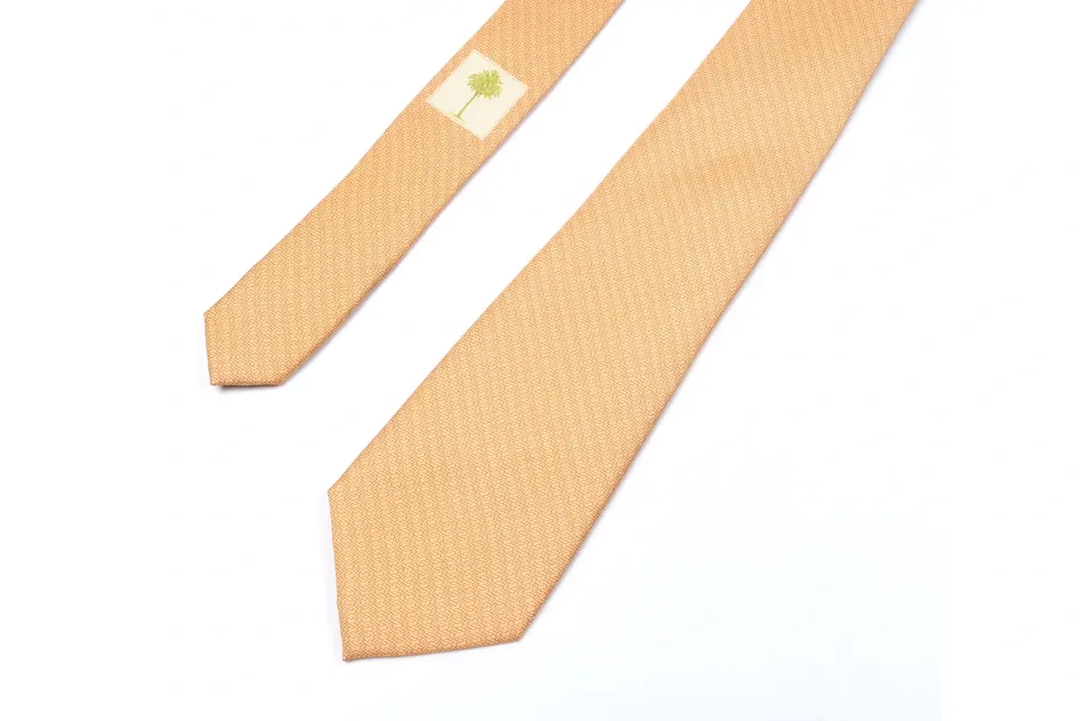 Pale gold tie with a small sewn label visible on reverse beside the front blade.