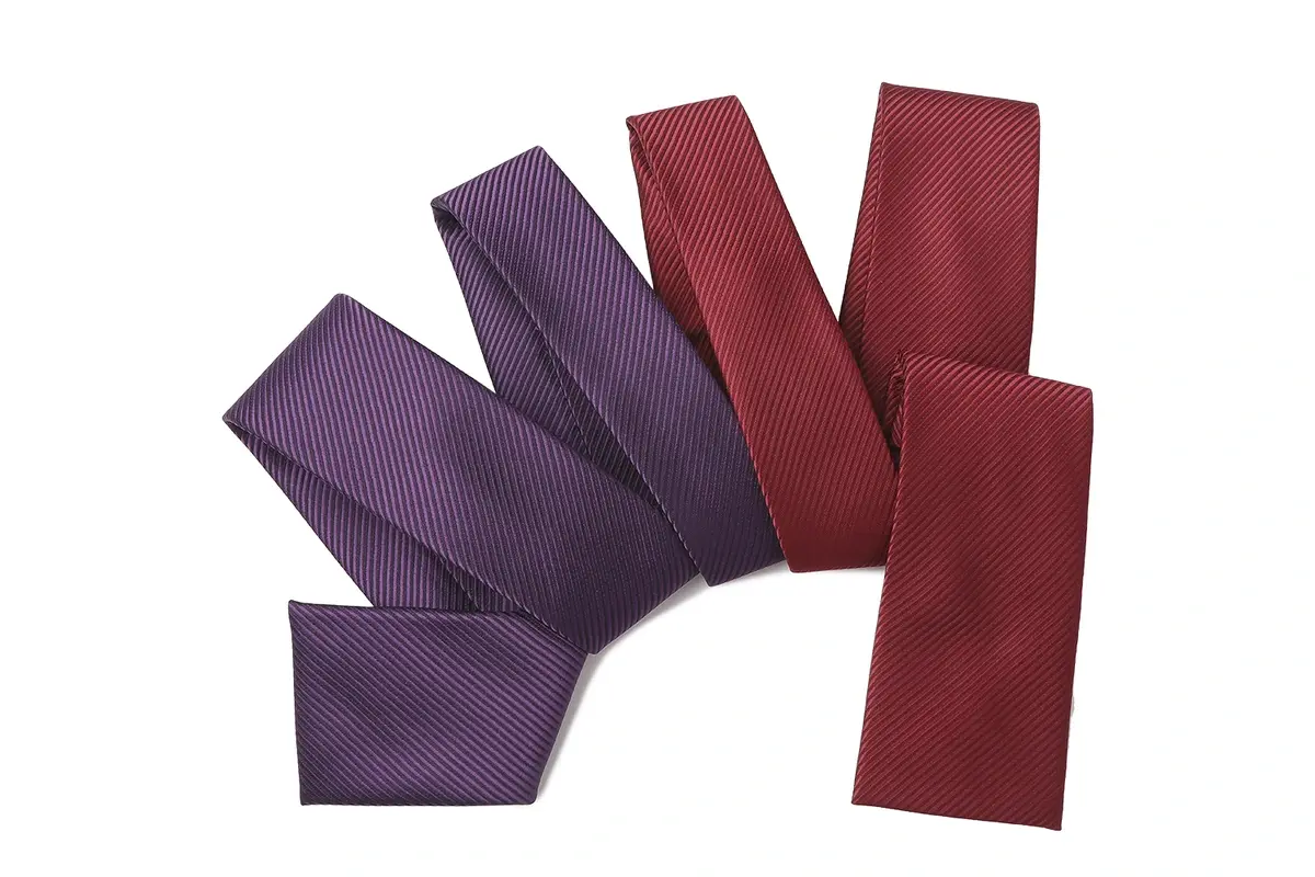 Purple and burgundy ties arranged to show their matching fine diagonal texture.