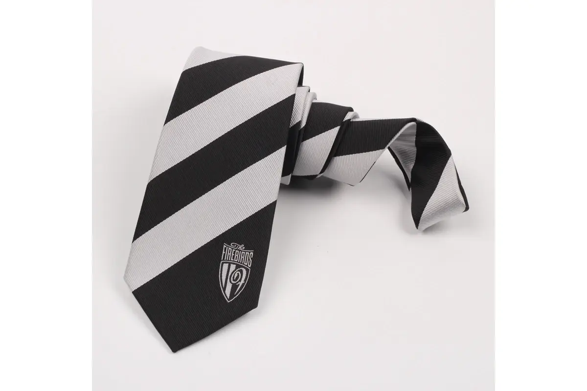 Black tie with broad pale diagonal stripes and small shield emblem near the tip.