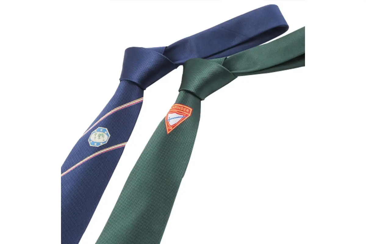 Navy and green knotted ties with single crests on the front blades.