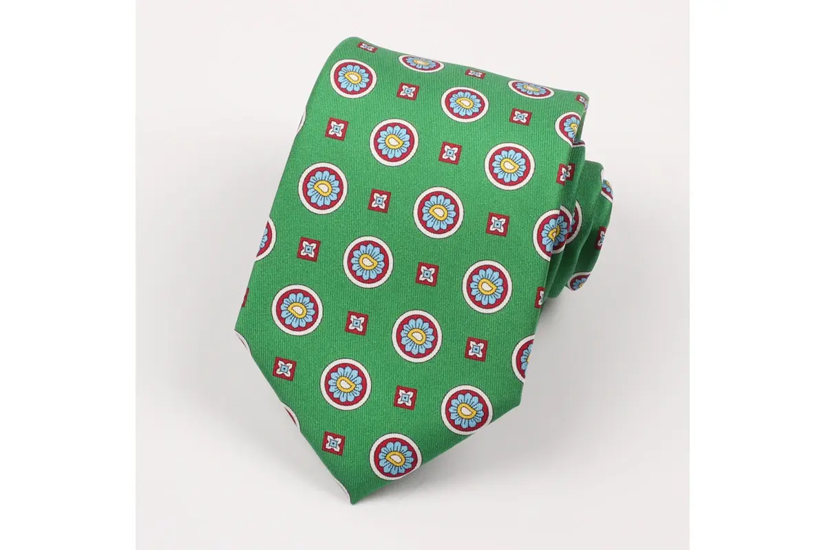 Green tie with repeated multicolor circular emblems and small square motifs.