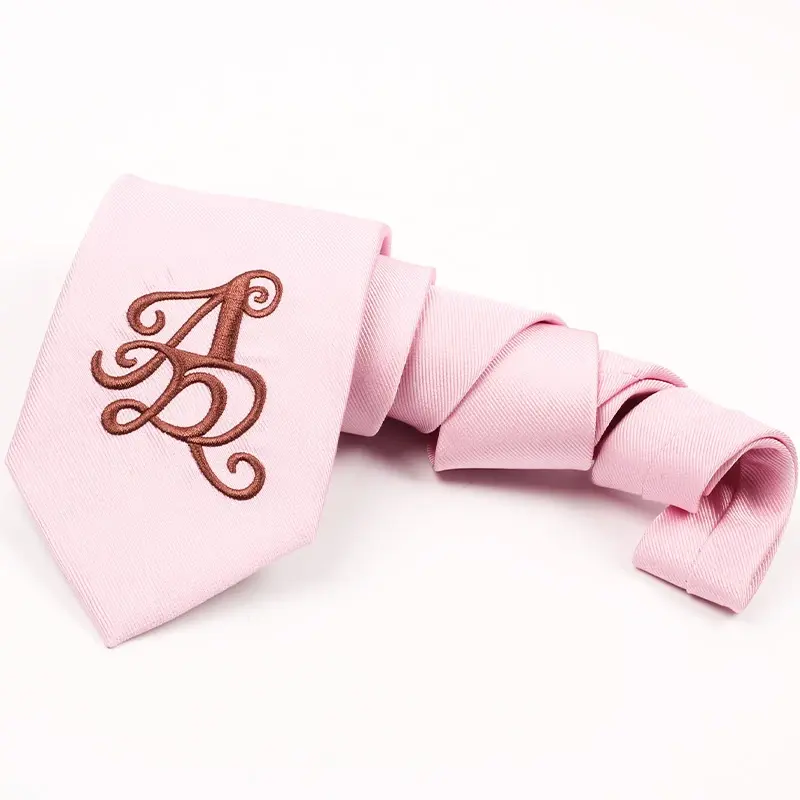 Pink tie with a large burgundy monogram near the front tip.