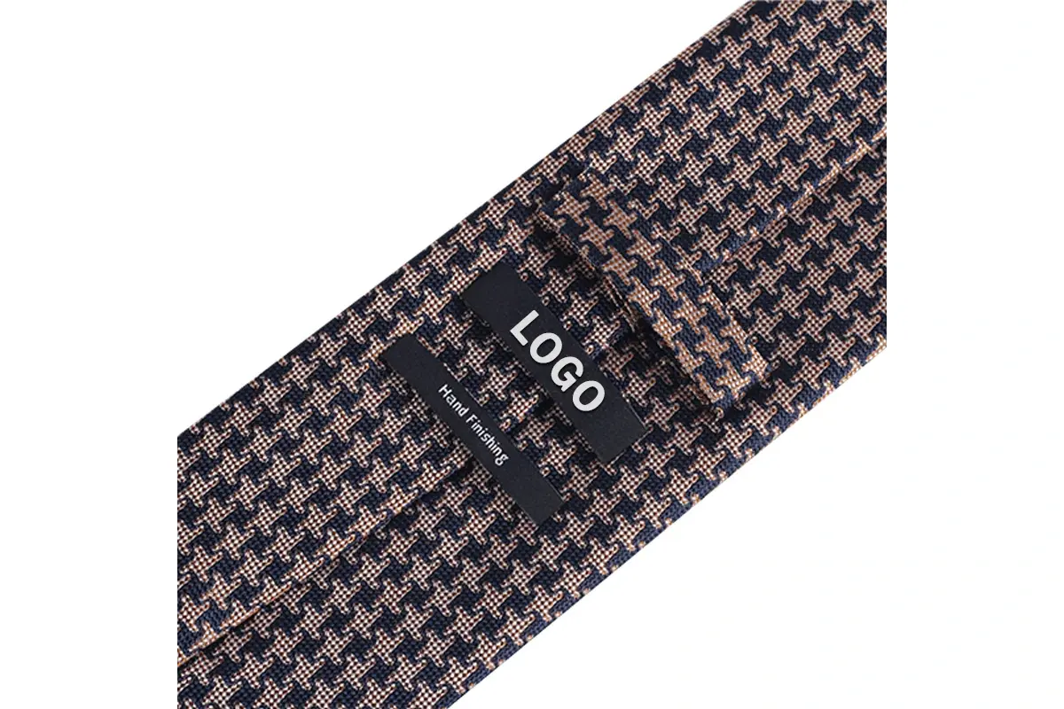 Black sample logo label sewn onto a brown and navy houndstooth tie.