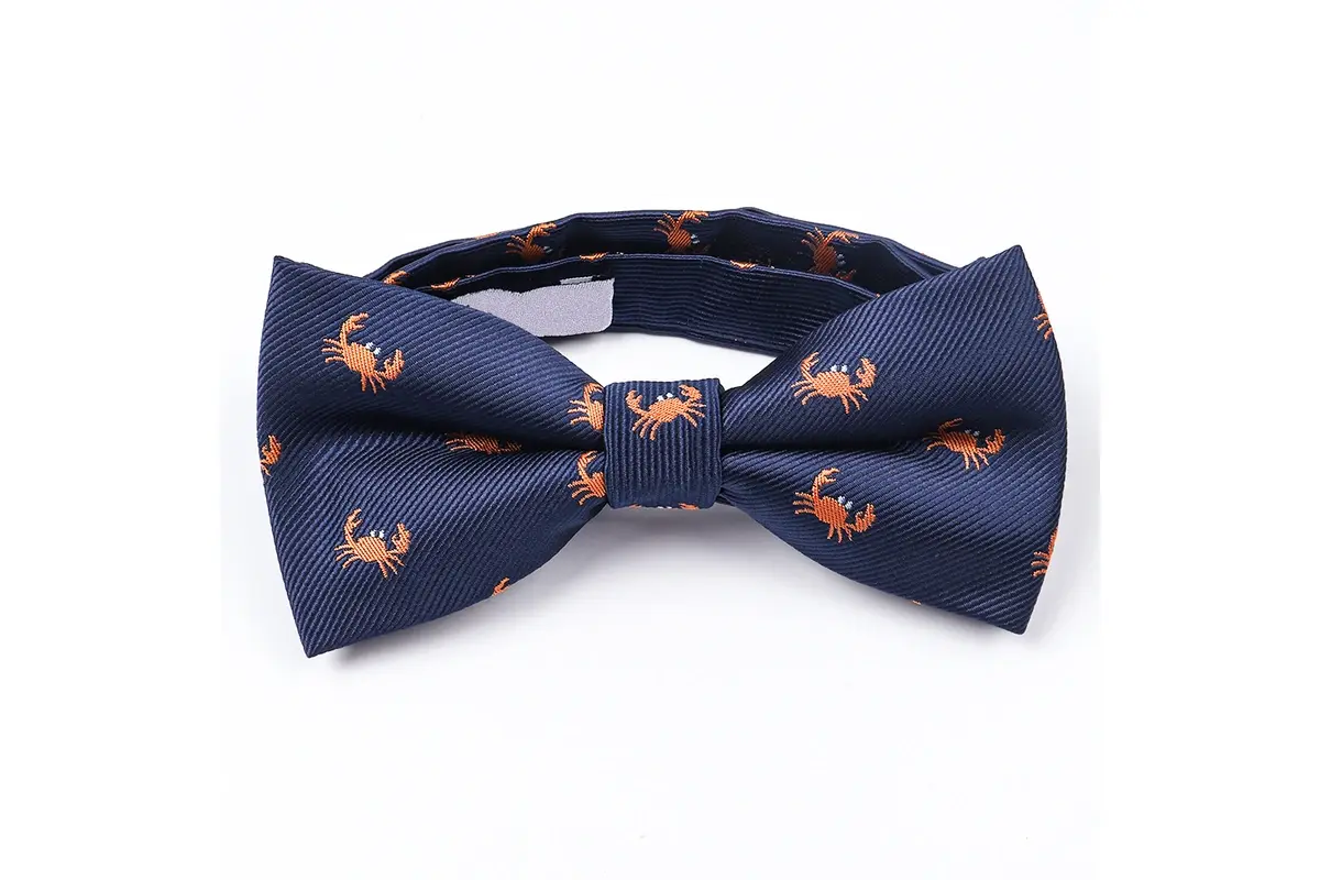 Navy pre-tied bow tie with small repeated orange animal motifs.