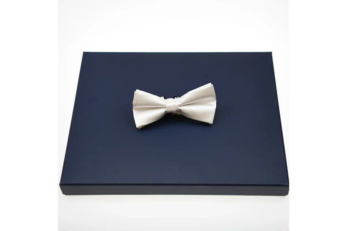 White bow tie displayed on a navy presentation box.