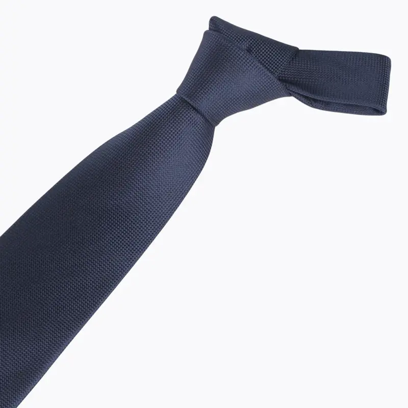 Navy necktie arranged in a loose knot on white