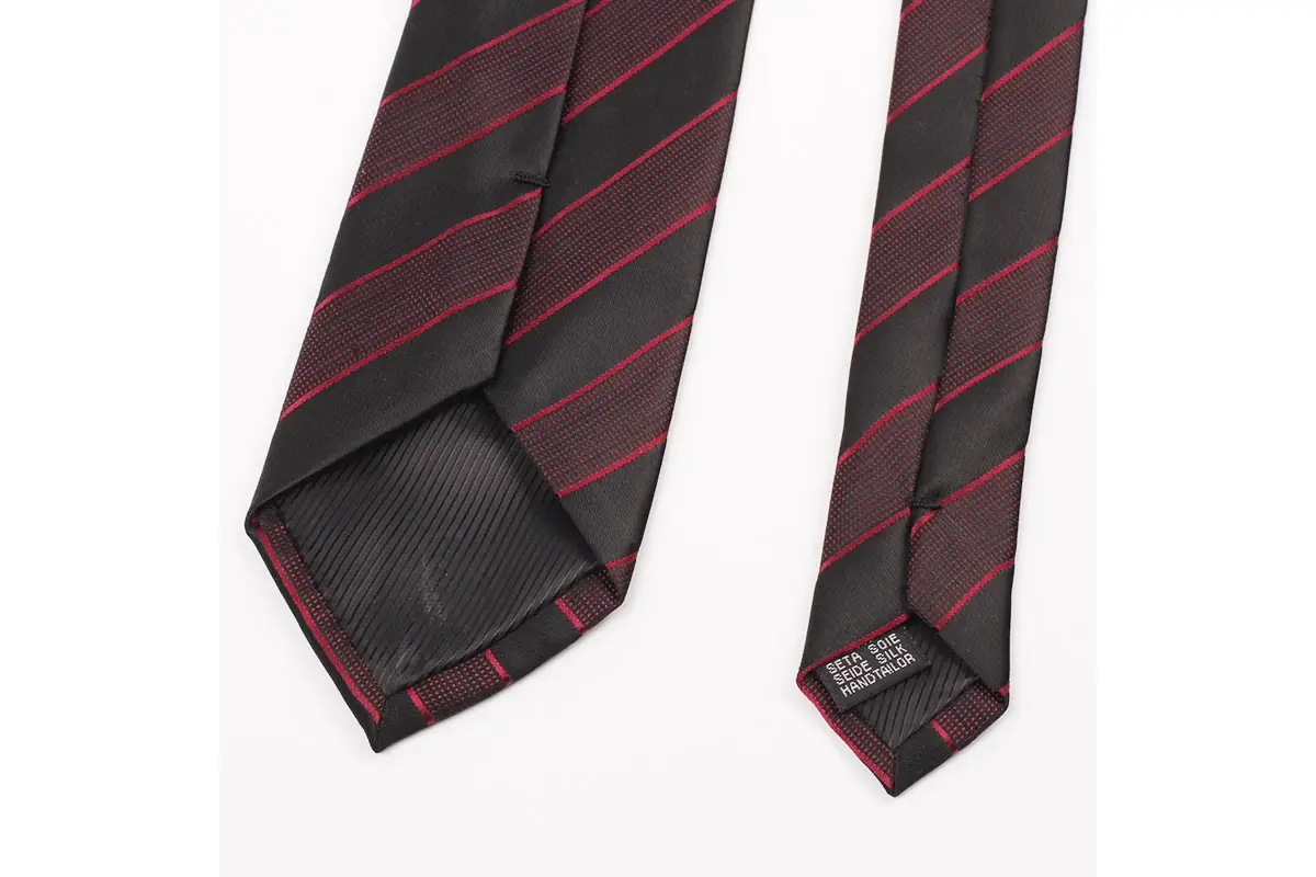 Dark tie with red diagonal stripes with reverse seams, tipping and care label.